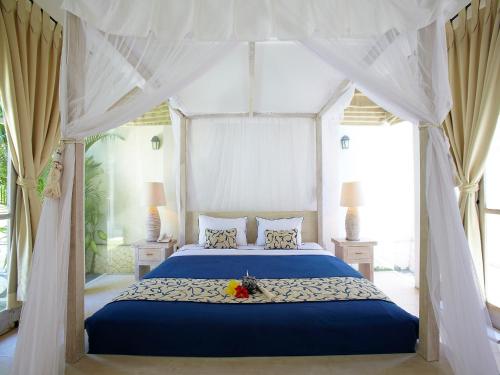 塞米亚克阿蒂米斯别墅酒店的一间卧室配有一张带天蓬的蓝色床