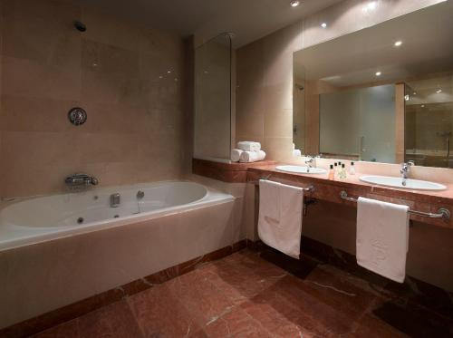 马拉加马拉加高尔夫旅馆的浴室设有2个水槽、浴缸和镜子