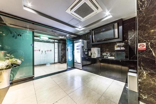 首尔吉姆斯汤姆吉酒店的一间设有厨房的客房,墙上配有电视
