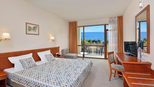 内塞伯尔Sol Nessebar Bay All Inclusive的酒店客房配有一张床、一张书桌和一台电视。