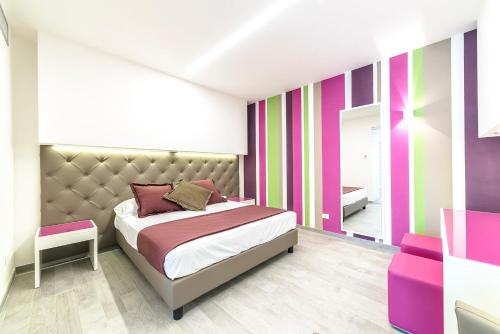 马瑞纳迪卡拉拉腾达罗萨酒店的一间卧室设有一张床和色彩缤纷的墙壁
