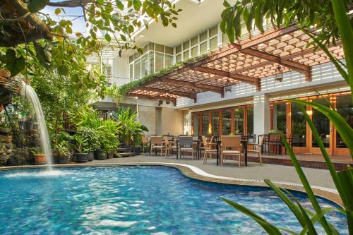 日惹Jambuluwuk Malioboro Hotel Yogyakarta的一个带喷泉的庭院内的游泳池