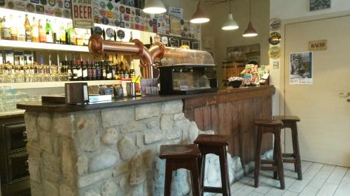 瓦尔玛德雷拉Locanda La Tana Del Luppolo的酒吧设有两个凳子和一个酒柜
