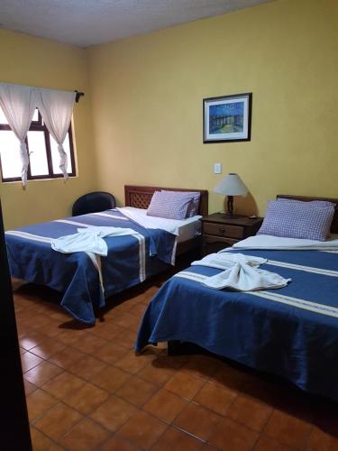 乌鲁阿潘Hotel Nuevo Cupatitzio的酒店客房设有两张床和窗户。
