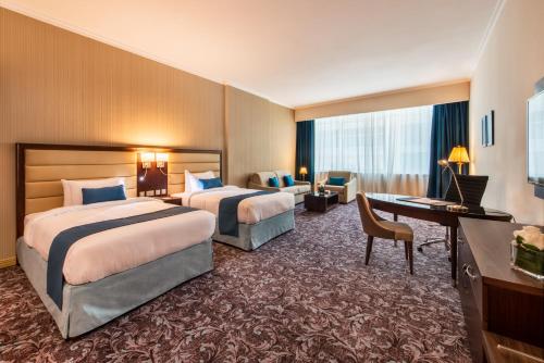 多哈多哈金色郁金香酒店的酒店客房配有两张床和一张书桌