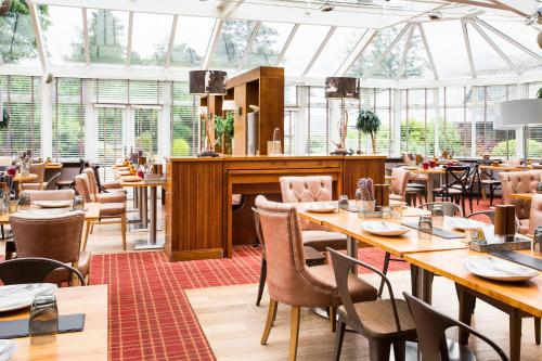 布罗迪克阿奇蕾妮度假酒店的餐厅设有木桌、椅子和窗户。