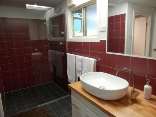 WondaiWondai Hideaway Apartment的红色瓷砖浴室设有水槽和淋浴