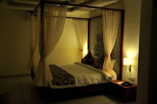 KhambhāliyaHotel Kalyan's - Mansingh Inn的卧室配有带白色窗帘的天蓬床