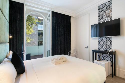 悉尼悉尼精品酒店的卧室配有一张床铺,墙上配有电视