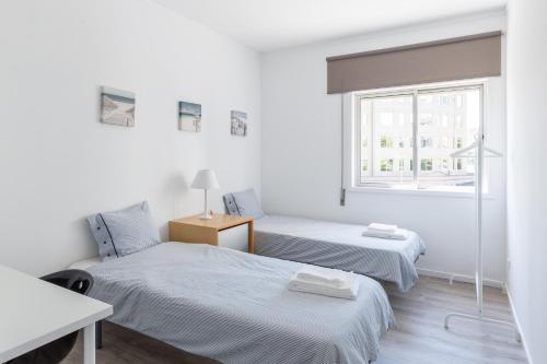 波尔图The Perfect Porto Apartment的白色客房的两张床,设有窗户