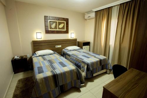 若阿萨巴Hotel do Comércio的酒店客房设有两张床和一张桌子。