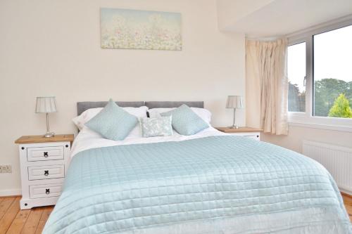 韦瑟比Riverside Cottage的一间卧室配有一张带蓝色棉被的床和窗户。
