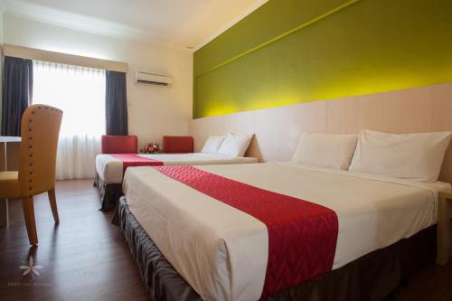峇六拜赛里马来西亚槟城岛酒店的酒店客房设有两张床和一张桌子。