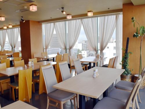 秋田秋田竿灯大街珍珠城市饭店的餐厅设有桌椅和大窗户。