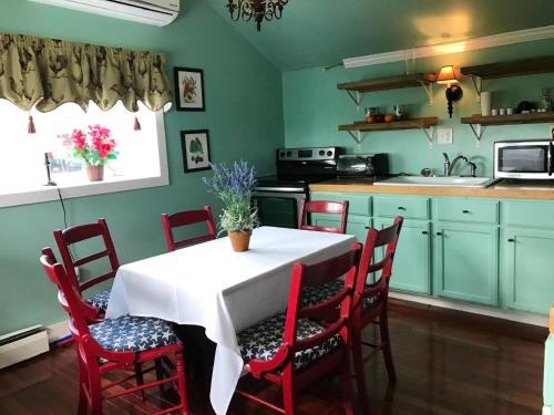 GrotonJohn Joseph Inn的一个带桌椅的厨房和一个带绿色橱柜的厨房