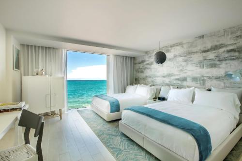 圣胡安Condado Ocean Club - Adults Only的酒店客房设有两张床和大窗户。