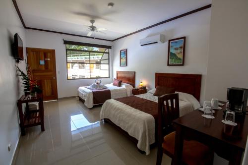 雅科Hotel Arenas en Punta Leona的一间卧室配有两张床、一张桌子和一张书桌