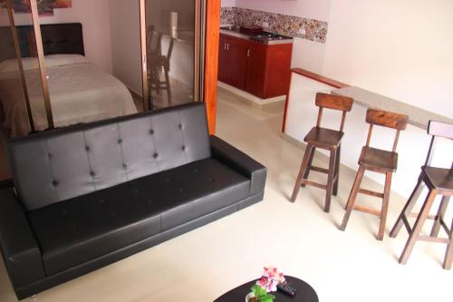 菲兰迪亚Apartahotel Calle del tiempo detenido的客厅配有黑色沙发和一些椅子