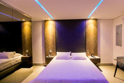 塞蒂拉瓜斯Hauss Excellence Motel的卧室配有一张白色大床和蓝色的灯光