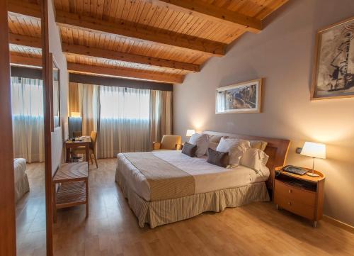 锡切斯巴塞罗那埃斯特拉酒店的一间带一张大床的卧室,位于一个拥有木制天花板的房间