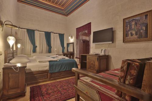 内夫谢希尔Yoruk Stone House的卧室配有一张床,墙上配有电视。