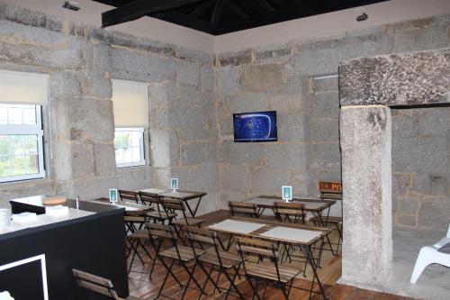Lagares da BeiraHostel Casa do Pinheiro的一间设有桌椅的房间和墙上的电视
