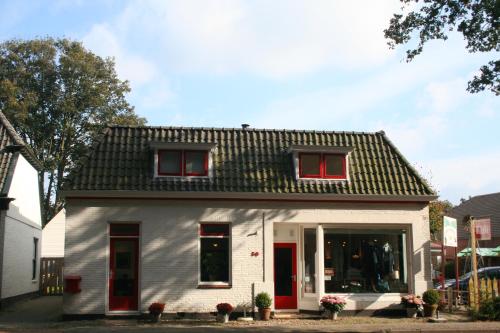 GlimmenBed & Breakfast Glimmen的一间白色的小房子,设有红色的门窗