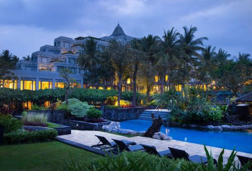 日惹凯悦日惹酒店的一座建筑前的带椅子和游泳池的酒店