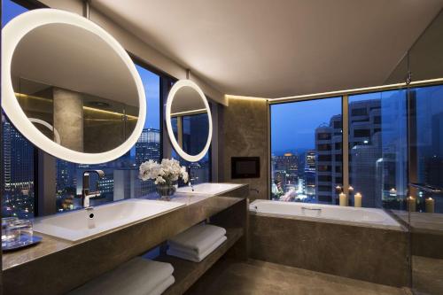台北台北君悦酒店的浴室配有2个盥洗盆、浴缸和镜子