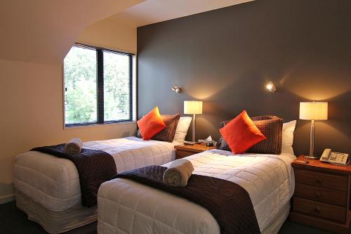 汉默温泉漂流者酒店的一间卧室配有两张带橙色枕头的床