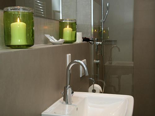 奥伯丁Hotel Gasthof Alte Post - Restaurant offen的浴室设有两个绿色蜡烛和一个水槽
