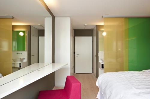 拉格斯索思丽餐厅酒店的卧室配有白色的床和粉红色的椅子