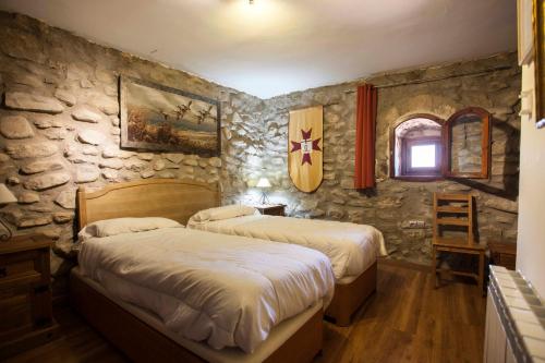 AñónCastillo de Añón de Moncayo的一间卧室设有两张床和石墙