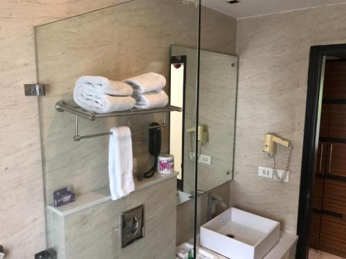 新德里象牙白32酒店的浴室设有镜子、水槽和毛巾