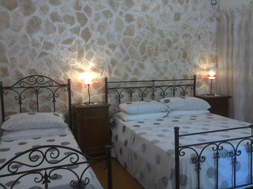 莫诺波利Trullocarluccio的一间卧室配有两张床,墙上有两盏灯