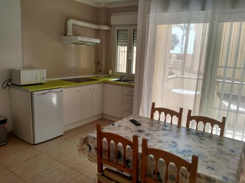 滨海罗克塔斯Apartroquetas的带桌椅的厨房和带窗户的厨房