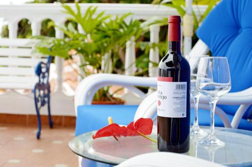 伊科德洛斯维诺斯德拉戈圣安东尼奥酒店的一瓶葡萄酒和一朵红花在桌子上