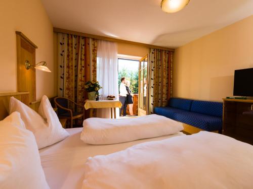 ArnfelsGasthof Hotel Schmied的一间设有两张床的酒店客房和一位女士从窗户望出去