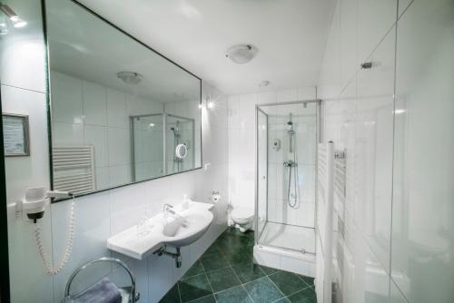 菲拉赫Stadthotel Kramer的白色的浴室设有水槽和淋浴。
