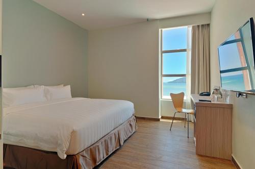 哥打京那巴鲁克拉甘酒店的一间卧室配有一张床、一张书桌和一个窗户。
