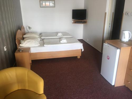 帕尔杜比采城市酒店的一间小卧室,配有一张床和一张黄色椅子