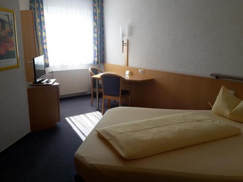 AlthengstettMotel Am Highway的配有一张床、一张书桌和一扇窗户的酒店客房