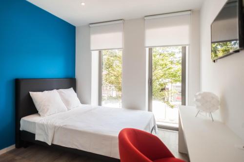 鲁汶鲁汶奥斯特2号酒店的卧室配有白色的床和红色椅子