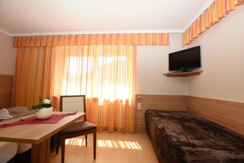 瑟弗浩斯基尼化玛旅馆的一间卧室配有一张床、一张书桌和一台电视