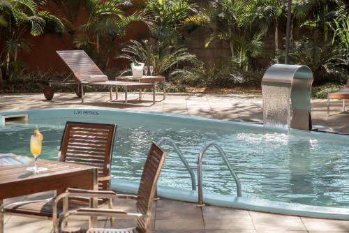 阿雷格里港Intercity Porto Alegre Aeroporto的一个带椅子和桌子的游泳池以及一个喷泉