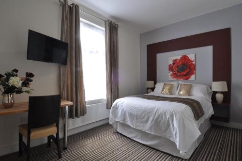 罗切斯特RBS酒店的一间卧室配有一张床、一张书桌和一台电视