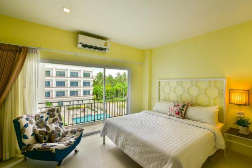 春蓬Southgate Residence Hotel - SHA Certified的一间卧室设有一张床、一个窗口和一把椅子