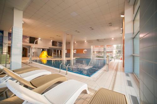 德兹维济诺Akces Medical Fit & Spa的大楼内一个带椅子和滑梯的游泳池