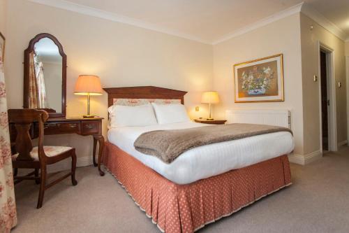 布里奇沃特The Walnut Tree Hotel的酒店客房带一张床、一张书桌和一面镜子