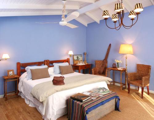 圣米格尔-德尔蒙特Estancia Los Patos的一间蓝色卧室,配有一张大床和两把椅子